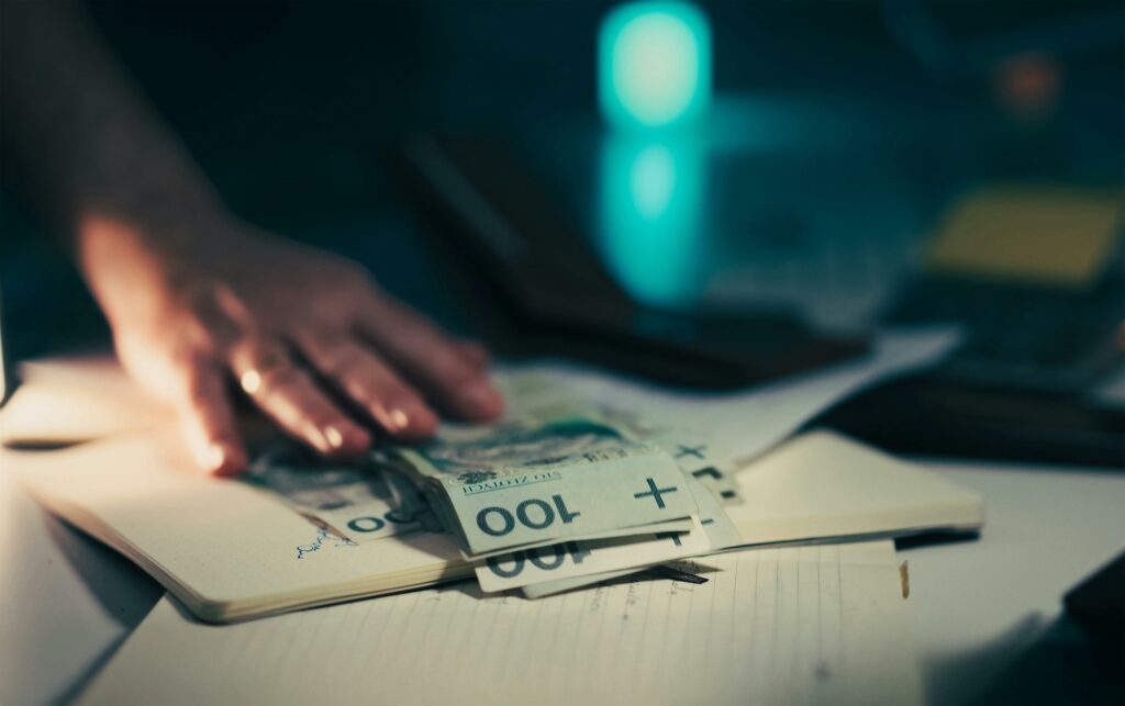 człowiek przesuwający banknoty po stole